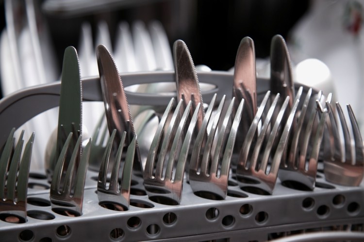 Knives and forks loaded prongs and sharp point up in dishwasher