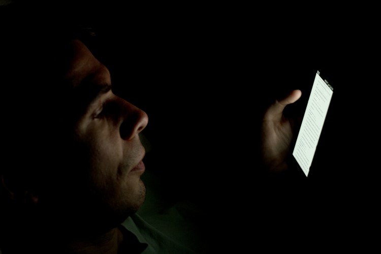 man looking at a cell phone in the dark